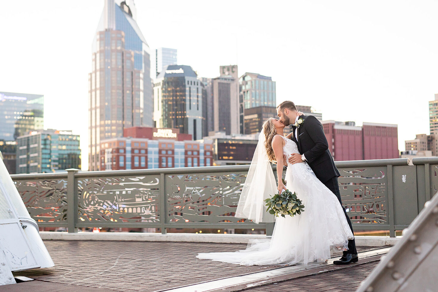 A romantic kiss shared between newlyweds on the pedestrian bridge in Nashville following their wedding ceremony at the Bridge Building. 