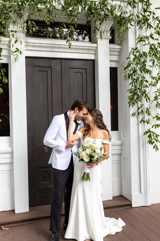 A newlywed couple standing on the front porch of Riverwood Mansion in East Nashville enjoying an intimate moment together before celebrating their wedding with family and friends.