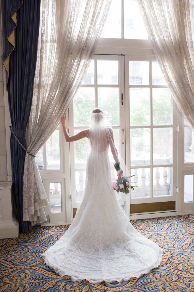 A beautiful bride looks out the windows of the Hermitage Hotel on her wedding day. 