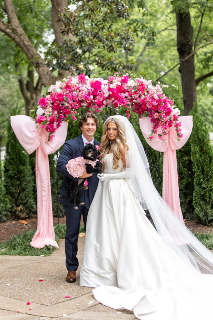 large pink floral wedding ceremony arch with large pink bows