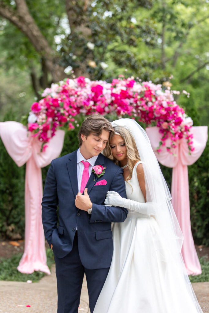large pink wedding ceremony arch with pink flowers and large pink bows