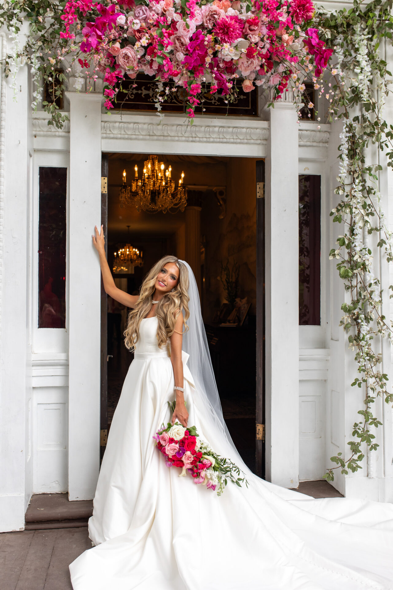 Beautiful blonde bride on the porch at Riverwood Mansion during her pink-themed wedding.